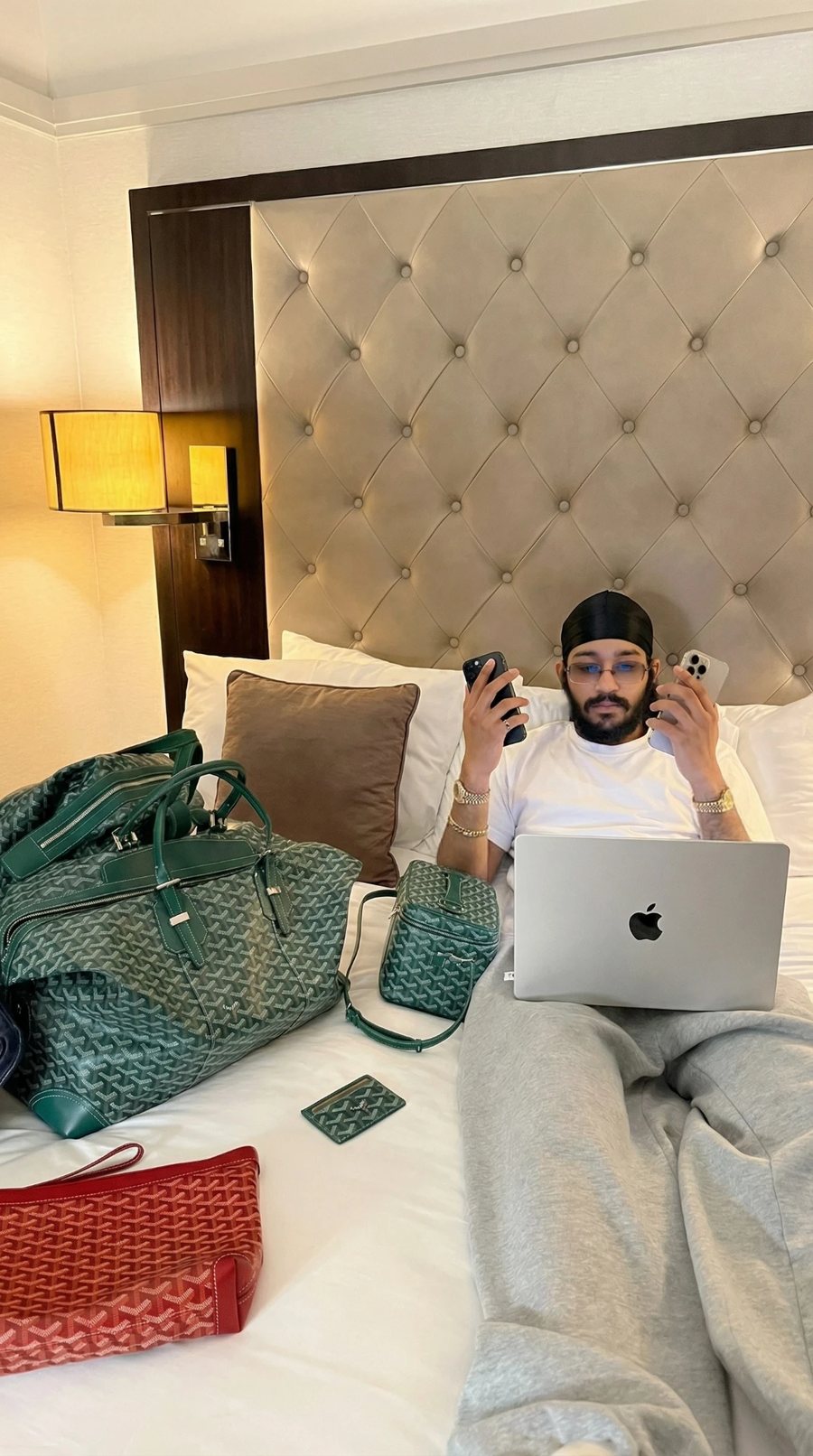 Jaidev Bhogal working on a laptop with two phones in a hotel room
